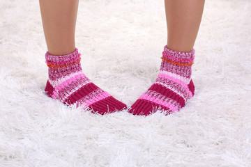 Female legs in colorful socks on white carpet background