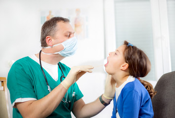 Fototapeta premium Doctor examining a girl's throat using a tongue depressor