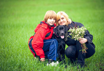 Happy family with Labrador is resting in the park