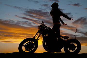 Obraz na płótnie Canvas Silhouette woman motorcycle stand hands back