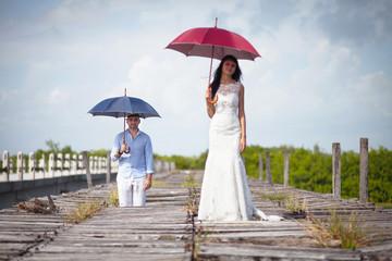 Beautiful couple of newly married stand on the bridge with umbre