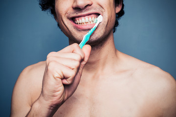 Happy young multi racial man brushing his teeth
