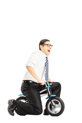 Fototapeta na wymiar Excited young businessperson riding a small bicycle