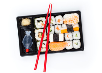 Delicious sushi rolls on white plate with chopsticks