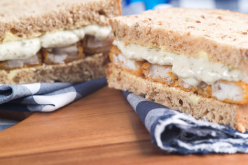 Fresh fish finger sandwich on wholegrain in rustic kitchen setti