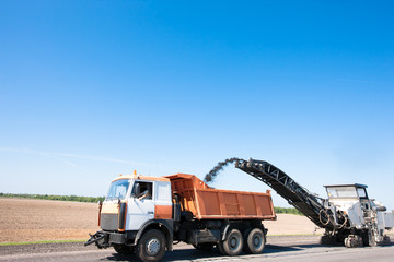 Milling machine loading worn asphalt into Dump Truck