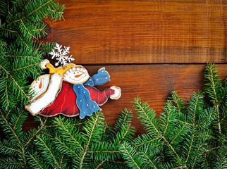 Branches of fir with snowman on wooden background