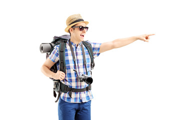 Smiling male tourist with backpack pointing with his finger