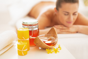Closeup on honey spa therapy ingredients and woman in background