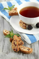 Cup of tea with cookies and blackberry on table close-up