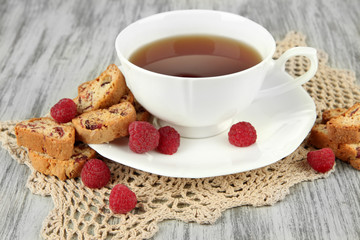 Cup of tea with cookies and raspberries on table close-up