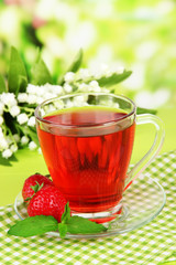 Delicious strawberry tea on table on bright background