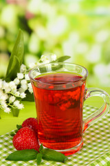 Delicious strawberry tea on table on bright background