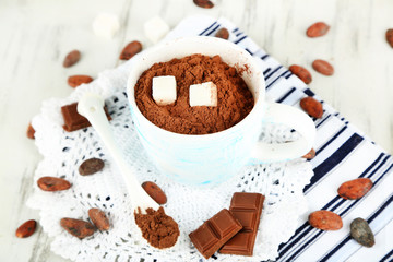 Cocoa powder in cup on napkins on wooden table