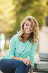 Obraz premium Portrait of a young beautiful smiling blonde woman outdoors