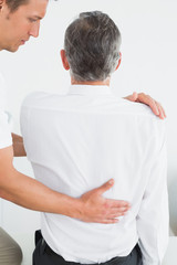 Obraz premium Male chiropractor examining mature man