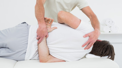 Obraz na płótnie Canvas Male physiotherapist examining man's back