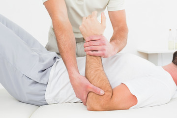 Fototapeta na wymiar Mid section of physiotherapist examining a man's hand