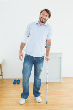 Full Length Portrait Of A Smiling Man With Crutch