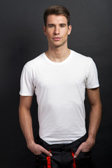 Handsome man posing in white tshirt on dark background in studio