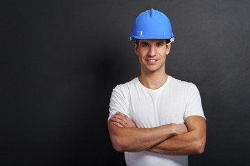 Young construction worker in hard hat on dark background