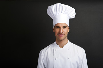 Chef cook against dark background smiling with hat
