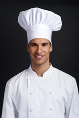 Chef cook against dark background smiling with hat