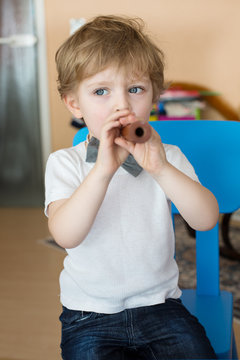 Little boy playing wooden flute indoor