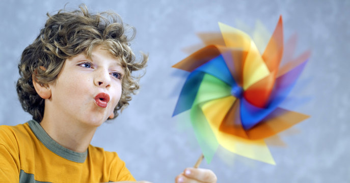 blonde child blowing a pinwheel