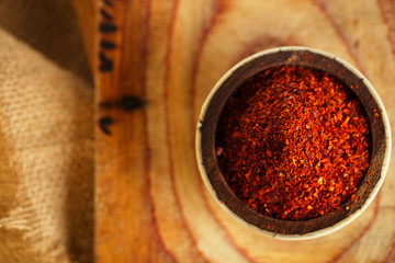 red hot chillies pepper  flakes in bowl on wooden board  backgro