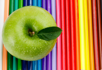 Colored pencils and a green apple