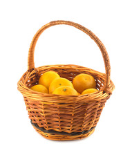Many orange tangerines in brown wicker basket isolated closeup