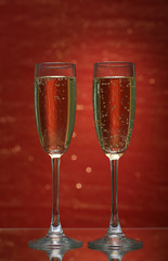 Two glasses of champagne on bright background with lights