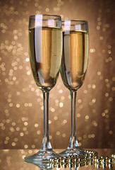 Two glasses of champagne on bright background with lights