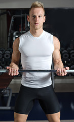 Fototapeta na wymiar Handsome young man training biceps lifting barbell