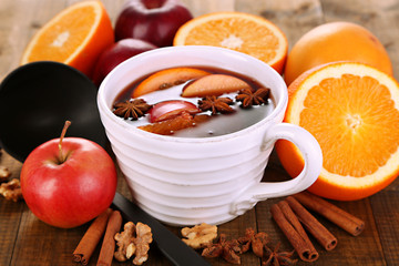 Fragrant mulled wine in bowl on wooden table close-up