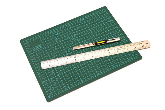 Green cutting mats with iron ruler and cuter isolated on white b