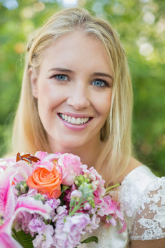 Happy bride looking at camera holding bouquet