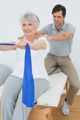 Fototapeta premium Male therapist assisting senior woman with exercises