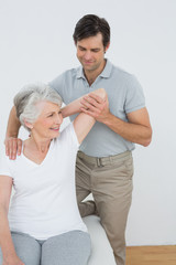 Fototapeta na wymiar Physiotherapist stretching a smiling senior woman's arm