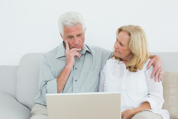 Senior couple using laptop on sofa