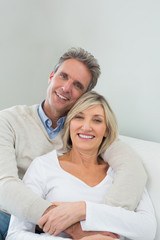 Happy couple embracing while sitting on sofa at home