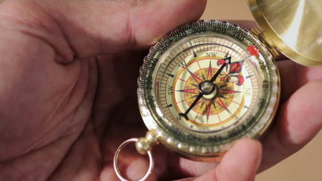 Hand holding a compass with swinging needle looking for North