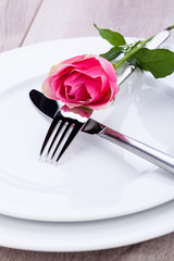 romantisch gedeckter tisch mit silberbesteck und einer rose