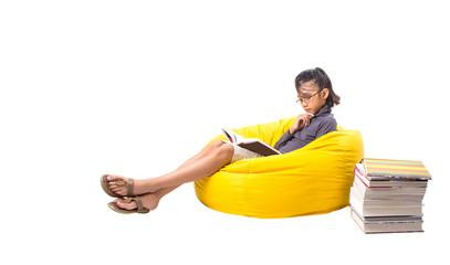 Young Malay Asian girl reading a book on a yellow bean bag