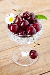 Fresh cherries in chrystal glass on wooden background