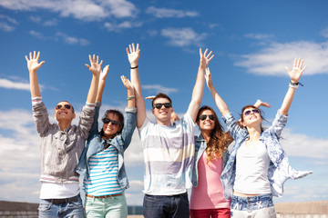 group of smiling teenagers holding hands up