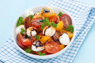 bowl of salad with mozzarella, balsamic sauce, colorful cherries