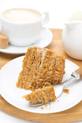 piece of honey cake on a plate, fork and cup of cappuccino
