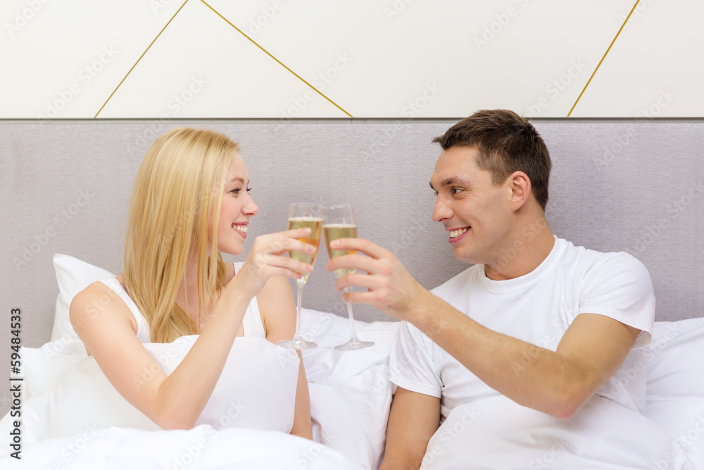 Canvas Prints smiling couple with champagne glasses in bed